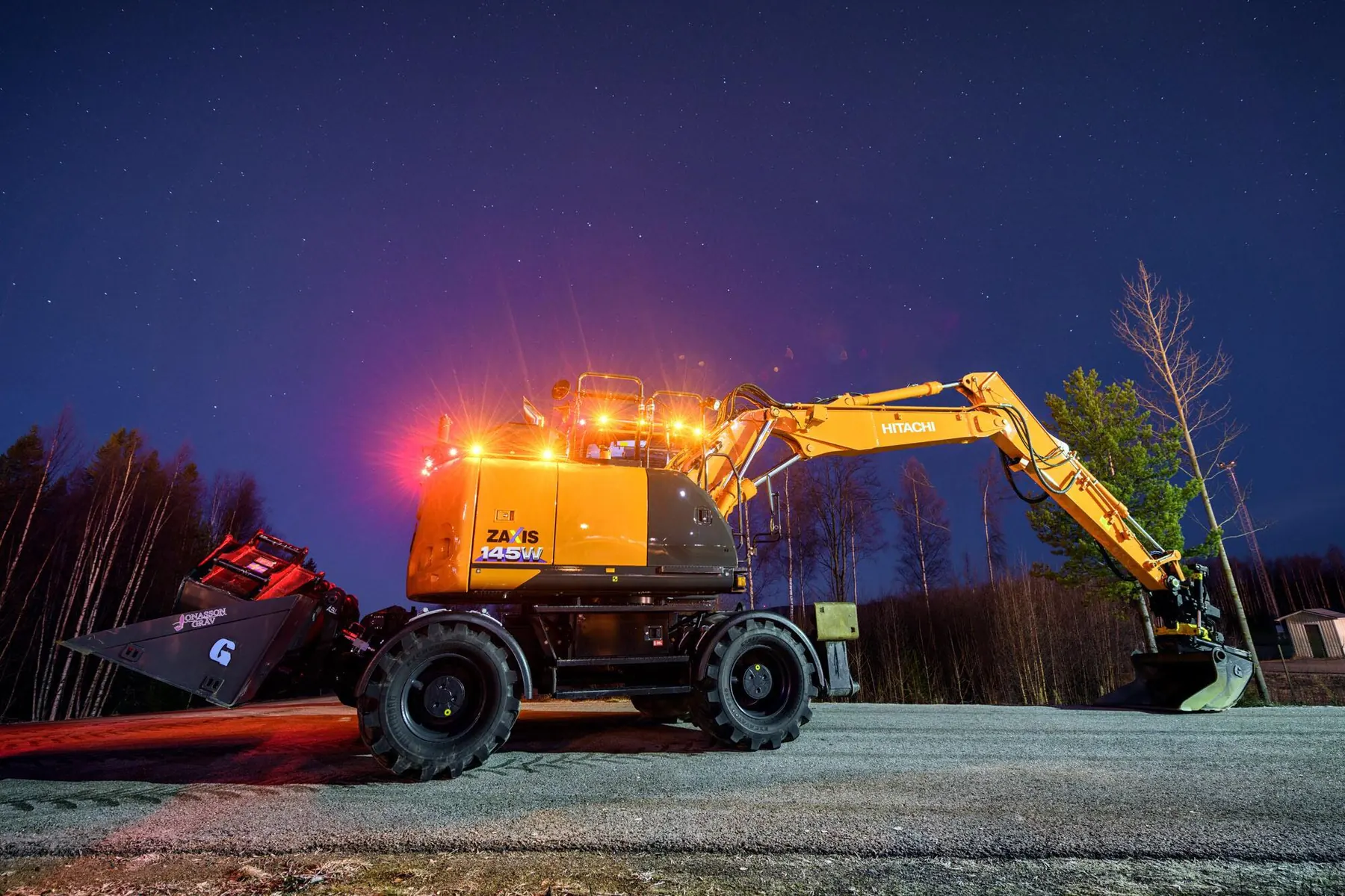Hitachi hjulgrävare med arbetsbelysning en vinterkväll